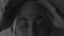 Video gif. Woman lays down in bed with her eyes closed. She pulls down a sleeping mask that has text that reads, “Let me sleep.” Over her eyes are drawings of closed eyes.