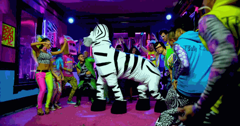 Pohyblivý gif s lidmi v kostýmu zebry obklopenými partou tancujících lidí. 