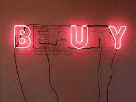 Text gif. Red neon block text installed on a wall reads "Beauty," but only certain letters light up, alternatingly spelling out "Eat" and "Buy."