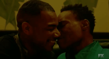 TV gif. With their faces close, Blake Morris as Keenan in Pose smiles and kisses Billy Porter as Pray Tell.