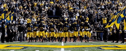 University of michigan football team running out after introductions with a massive crowd behind them