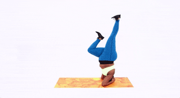 Video gif. Curvy woman does upside down splits on a yoga mat.