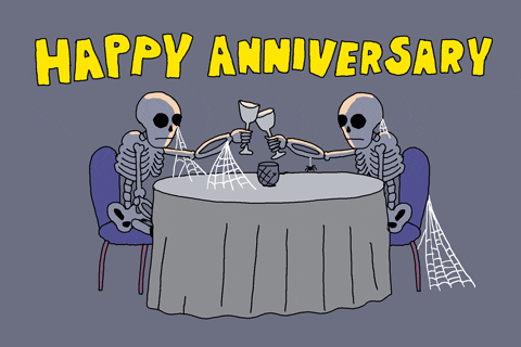 Obrázek se dvěma sedícími kostrami u stolu, připíjejícími si poháry s pohyblivým nápisem Happy anniversary. 