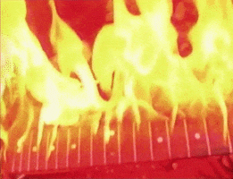 Video gif. Close up shot of fire burning an electric guitar.