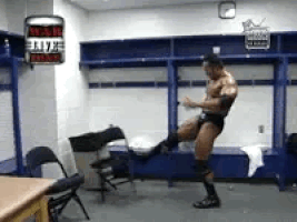 Sports gif. The Rock from WWE is throwing a tantrum in the locker room and is flipping and destroying everything he can get his hands on. He's still wearing his wrestling speedo as he throws his temper tantrum.
