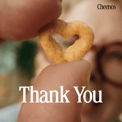 Sponsored gif. In the foreground, two fingers hold a heart shaped Cheerio. A figure wearing dark rimmed glasses is blurred behind it, mouthing the words "thank you." The Cheerios logo is in the upper right corner. Text reads: Thank you. 