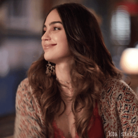 TV gif. Melissa Barrera as Lyn on Vida shakes her head and raises her arms in excitement.