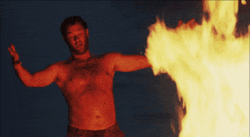 Movie gif. Tom Hanks as Chuck in Cast Away stands shirtless in front of a massive yellow fire. He holds out his arms, looks at the fire, then turns to the void beside him. Subtitles, "Look what I have created!"