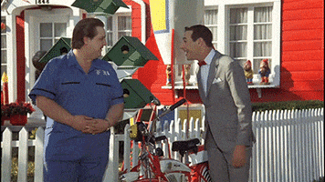 TV gif. Paul Reubens as Pee Wee Herman begins to laugh so hysterically that he falls over, rolling on the floor.
