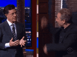 TV gif. The Late Show host Stephen Colbert high fives an air-boxing guest.