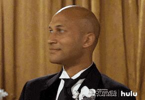 Celebrity gif. Keegan-Michael Key, a light-brown man in a black suit and tie wears a boutonniere. He swings his head around and glances forward, mouth opening wide, face beaming with laughter. 