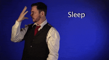 Video gif. A man is teaching us the American Sign Language word for sleep. He puts his hand in front of his face and brings all fingers together while simultaneously closing his eyes and tilting his head down.