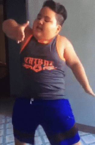 Video gif. A young boy dances happily, his hands moving from his chest to his upper legs as he moves.