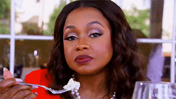 Reality TV gif. Phaedra Parks on Real Housewives of Atlanta holds a fork with a bite of food on it. While she takes a bite of her food, she rolls her eyes. 