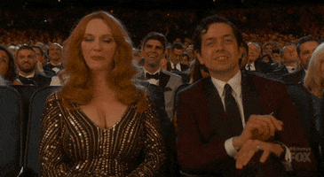 Celebrity gif. Christina Hendricks wears an ornate gown in an audience as she rolls her eyes.