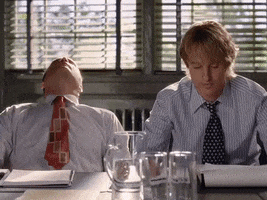 Movie gif. Vince Vaughn as Jeremy and Owen Wilson as John in Wedding Crashers seated on one side of a conference table, wearing button-up shirts and ties, looking frustrated and bored beyond belief.