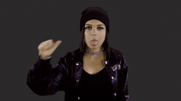 Video gif. EvieWhy sticks out her tongue at us while giving a thumbs down sign.