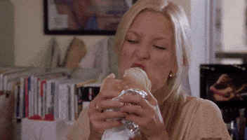 Movie gif. Kate Hudson as Andy Anderson in How to Lose a Guy in Ten Days exaggeratedly bites into a hamburger. She rolls her eyes and melts as if its the best burger in the world.