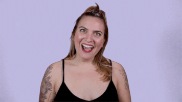 Video gif. Woman tilts her head with a sarcastic smile as she lifts up two middle fingers.