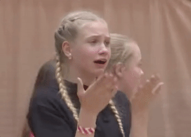 Video gif. A girl with braids and braces looks uncomfortable as she fans her face with her hands. 