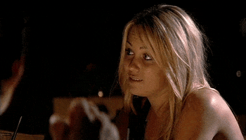 Reality TV gif. Lauren Conrad from The Hills sits in front of a bonfire and pouts her lips in faux sadness. She raises her hands and crosses both her fingers before looking down.