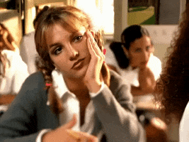 Music video gif. Britney Spears in her video for Baby One More Time rests her chin in her hand and absently plays with a pencil as she glances to the side with boredom.