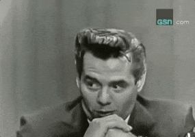 Celebrity gif. Desi Arnaz rests his mouth on his fists as his eyes dart back and forth.