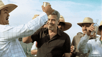 Ad gif. George Clooney in a circle of men wearing straw hats, raising up glasses and bottles of Casamigos tequila to cheers.