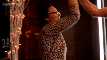 Reality TV gif. Contestants from Blown Away give each other a happy high five and one of them says, "Proud of you."