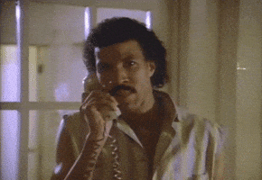 Celebrity gif. An emotional Lionel Richie sings into the phone, “Hello? Is it me you're looking for?” A woman on the other line lies in bed in her pajamas, holding the receiver to her ear and smiling.