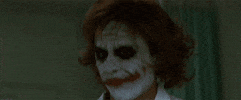 Movie gif. Dressed as a nurse in full Joker makeup, Heath Ledger as The Joker in The Dark Knight smiles creepily and says, “hi.”