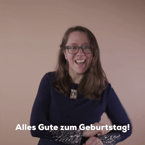 Reaction gif. A Disabled Latina woman with brown wavy hair and glasses smilingly explodes her jazz hands in an outward arc, shouting "Alles Gute zum Geburtstag!"