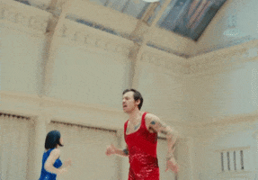 Music video gif. Harry Styles in As It Was jogs in place in a gym, singing as we move closer to him. 