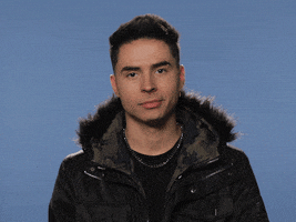 Celebrity gif. Reykon, a Colombian reggaeton artist, raises an eyebrow at us and shrugs his shoulders, leaning to the left. 
