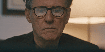 Movie gif. Gabriel Byrne as Steve in Hereditary. He has glasses on and is looking at something as he researches. His finger goes up to his lips and he is in deep thought.