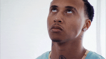 Video gif. Man looks up at the sky with a sad expression on his face, like he’s silently praying.