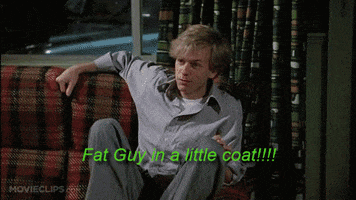 Movie gif. Chris Farley as Tommy and David Spade as Richard in Tommy Boy. Tommy is standing in front of Richard, who sits on a couch, and he's wearing a very small coat. He yells, "Fat guy in a little coat!!!" and shoves his arms forward, which rips the coat open from the back in one huge seam.