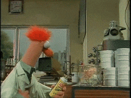 Muppets gif. Beaker, in a laboratory, uses a can of gas to light something on fire. When the flames shoot up toward the ceiling, he immediately panics--looks like that's a science experiment gone wrong.