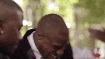 Reality TV gif. Ray J and Roccstar are on Love & Hip Hop: Hollywood and Roccstar is busting up and something Ray J said. He bounces out of his seat as he laughs and they both hold cigars.