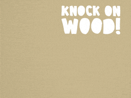 Video gif. Hand pops up in a fist and then a plank of wood pops up next to it. The hand knocks on the piece of wood. Text, “Knock on wood!”