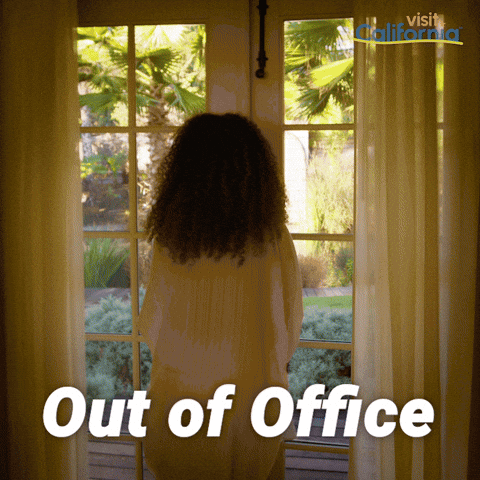 Sponsored gif. Woman in a gauzy white outfit walks through glass double doors into a lush California garden that features palm trees, a pond, and a fountain. Text reads, “Out of Office.”