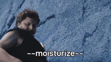Sponsored gif. Michael Cera is scaling a rock wall and he reaches down to his hip pack. We expect him to bring out climbing chalk, but instead, he scoops out handful of lotion and carefully slathers it on the rock face, slowly running his hand down while saying, "Moisturize." 