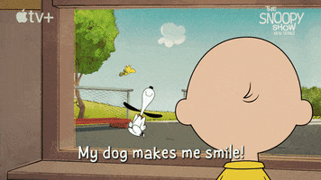 Peanuts gif. From a window, Charlie Brown smiles and watches Snoopy jump happily while Woodstock circles overhead. Text, "My dog makes me smile!"