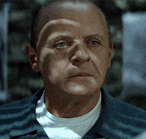 Movie gif. Dramatically lit and wearing his prison uniform, Anthony Hopkins as Hannibal Lecter from The Silence of the Lambs speaks to us with a straight face, then gives us a creepy smile. Text, "Thank you."