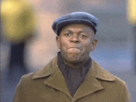Video gif. A man on a street wearing a coat and newsboy cap with a tight, proud expression on his face gives a slow clap.