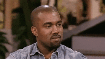 Celebrity gif. Kanye West smiles with a chuckle, then abruptly turns to the side with a pout.