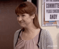 The Office gif. Closeup on Ellie Kemper as Erin as she excitedly crosses her fingers on both hands.