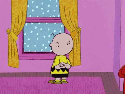 Peanuts gif. A sad Charlie Brown stands at a window, watching the snow as it falls.