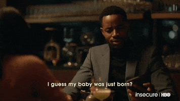 TV gif. Jay Ellis as Lawrence in Insecure. He's at a fancy dinner wearing a suit and he looks down confusedly at his phone while saying, "I guess my baby was just born?"