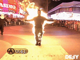 TV gif. Surrounded by a crowd in front of a casino, an on-fire Criss Angel spreads his arms and yells.